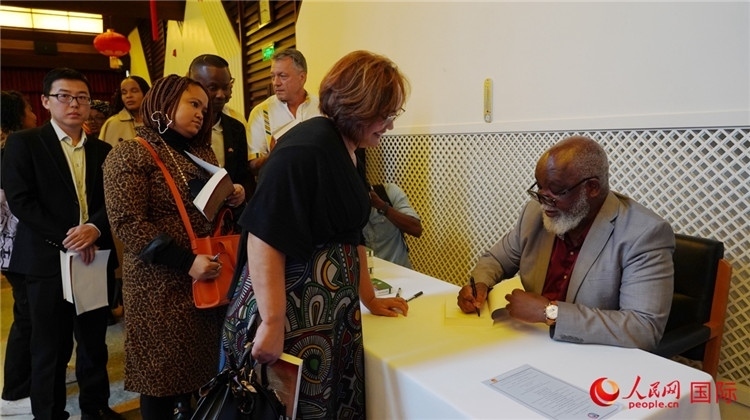 譚哲理在活動現(xiàn)場簽名贈書。人民網(wǎng) 劉暢攝