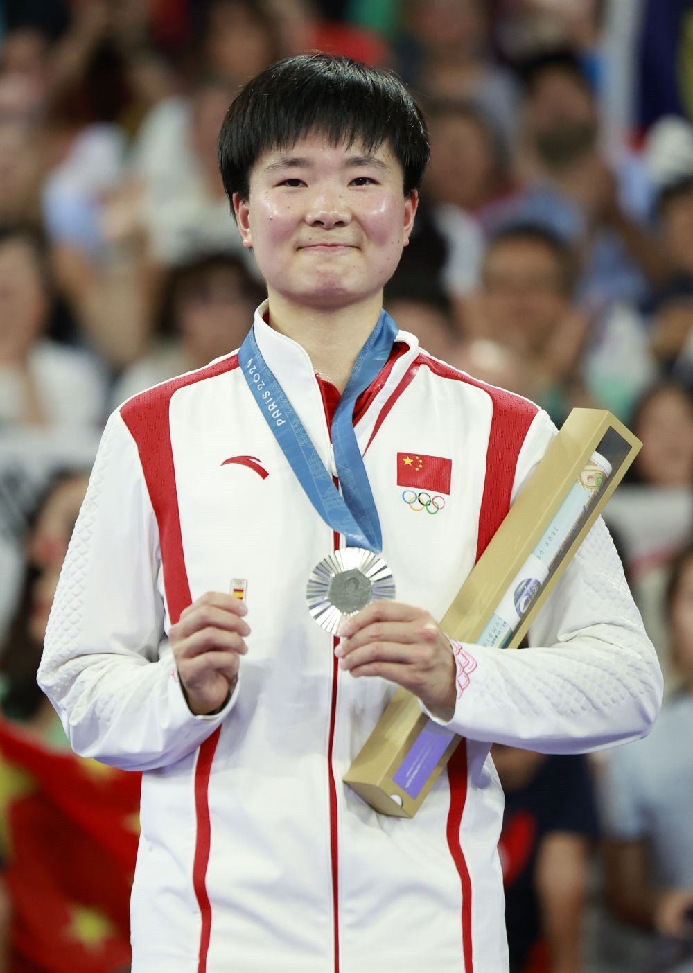 巴黎奧運會羽毛球女子單打亞軍、中國選手何冰嬌在頒獎儀式上一手握著銀牌，一手握著西班牙奧委會徽章（2024年8月5日攝）。新華社記者 任正來 攝