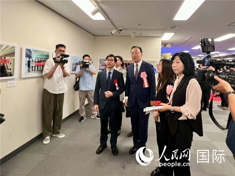 中國(guó)國(guó)際航空日韓地區(qū)支社支社長(zhǎng)馮力為中國(guó)駐日本大使館臨時(shí)代辦施泳等嘉賓介紹展出圖片。人民網(wǎng) 許可攝