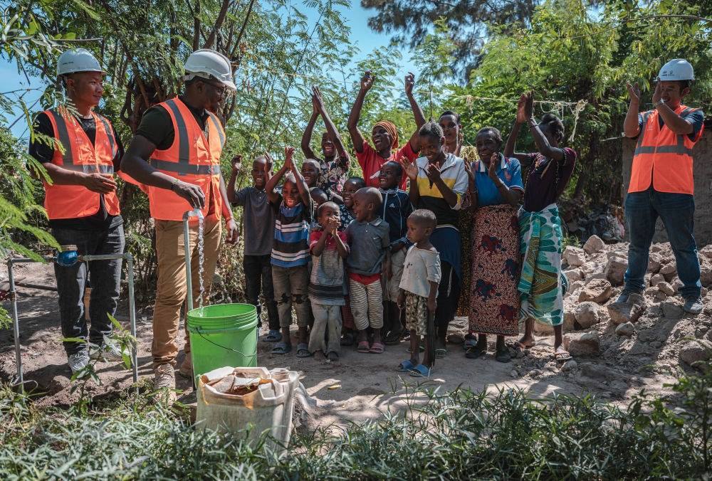 2023年6月13日，在坦桑尼亞姆萬(wàn)扎省米松圭，工作人員接通水管后贏得當(dāng)?shù)鼐用窆恼茪g呼。新華社記者 王冠森 攝