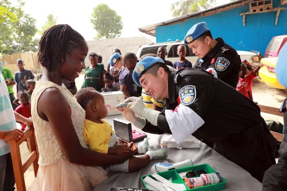 2017年12月28日，在利比里亞蒙羅維亞，中國維和警察防暴隊醫(yī)療人員為兒童做口腔檢查。