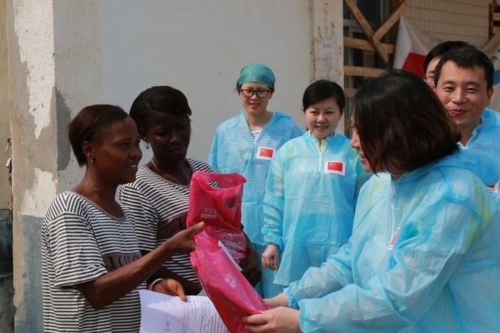 2015年4月4日，在位于塞拉利昂首都弗里敦市郊的中塞友好醫(yī)院埃博拉診療中心，中國(guó)第四批援塞醫(yī)療隊(duì)副隊(duì)長(zhǎng)邵蔚（右前）向被治愈的埃博拉出血熱患者贈(zèng)送禮物。新華社發(fā)（祖榮強(qiáng) 攝）