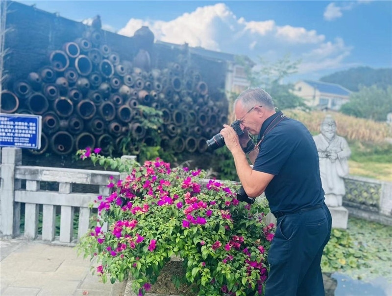 遠(yuǎn)處黔北民居錯落有致，近處一只黑色的蝴蝶穿梭于粉紫色三角梅花叢間隙，與俄羅斯“大歐亞”總編輯弗拉基米爾·別列日內(nèi)赫的鏡頭玩起了捉迷藏，“你追我逃，不亦樂乎”。（張亞欣攝）