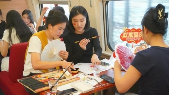10月1日，旅客們在G1634次列車上給油紙傘作畫。新華社記者周義 攝