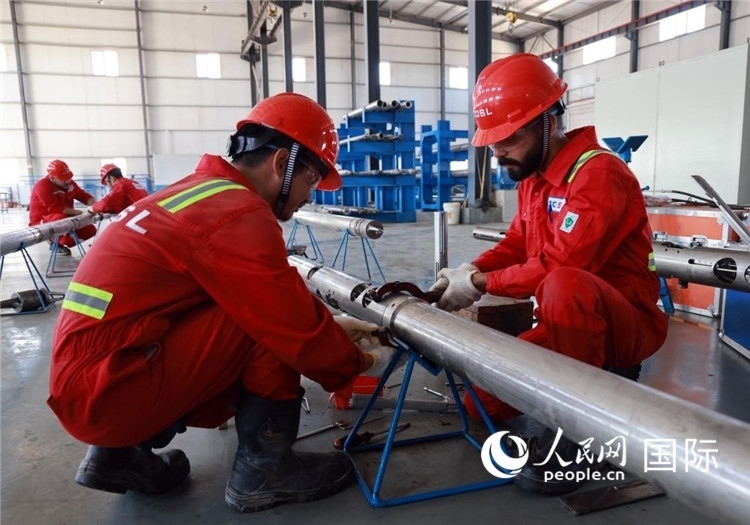 中伊員工共同在檢修鉆井設(shè)備。人民網(wǎng)記者管克江攝