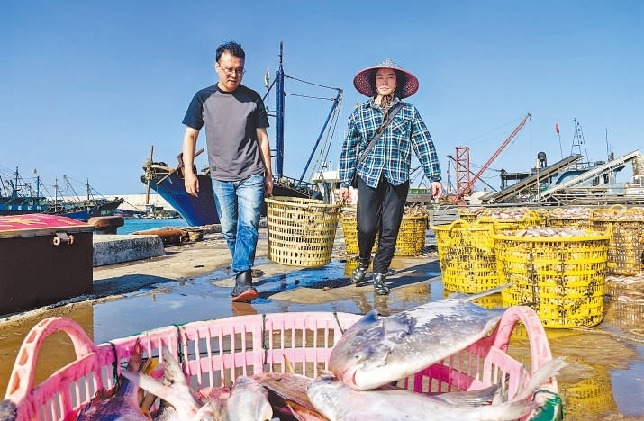 許小斌（左）和漁民一起搬運(yùn)海鮮。本報記者 付 文攝