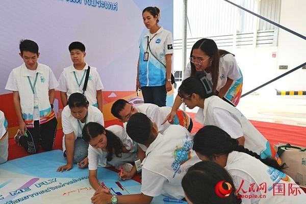 泰國(guó)學(xué)生在開營(yíng)儀式展板上繪制圖案。人民網(wǎng)記者 白元琪攝