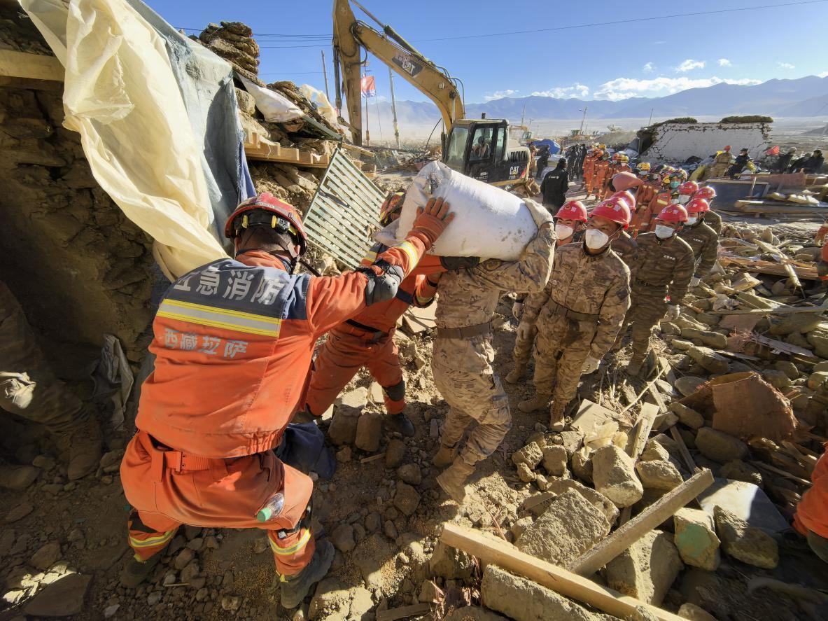 1月11日，定日縣長(zhǎng)所鄉(xiāng)古榮村，應(yīng)急消防等救援人員排隊(duì)接力搶運(yùn)掩埋在倒塌房屋下的群眾財(cái)物。人民日?qǐng)?bào)記者楊翹楚攝