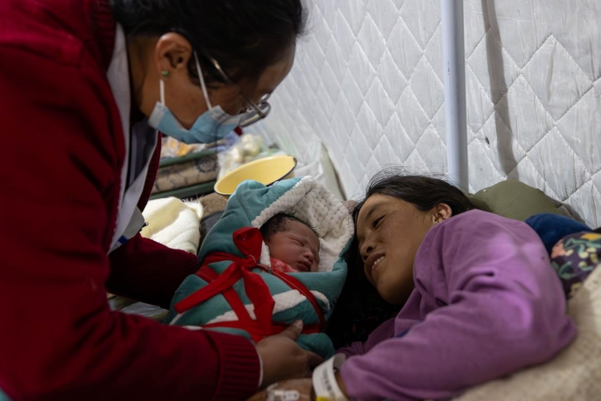 1月10日，定日縣中心醫(yī)院的婦產(chǎn)科醫(yī)生悉心照看一位母親和她懷里的新生兒。人民日?qǐng)?bào)記者張武軍攝