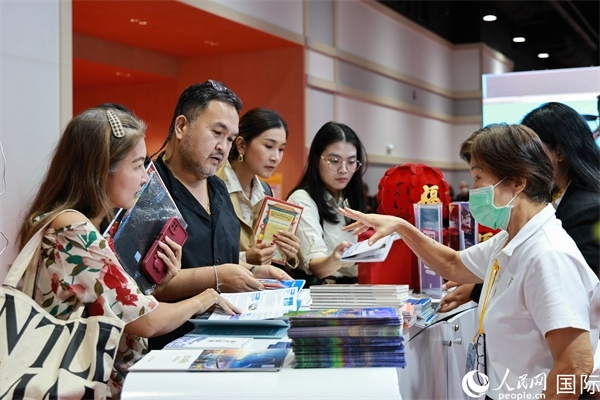 外國(guó)觀眾在中國(guó)展臺(tái)仔細(xì)閱讀赴華旅游介紹，向工作人員咨詢關(guān)于中國(guó)美食和景點(diǎn)的詳細(xì)信息。人民網(wǎng)記者 白元琪攝
