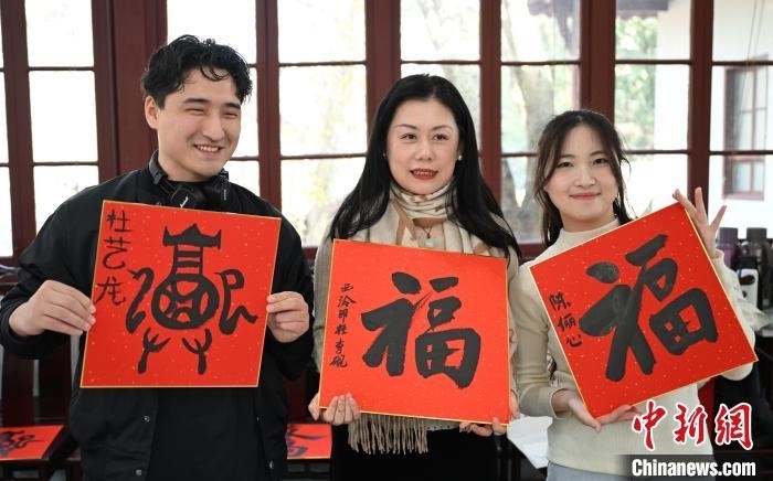 1月20日，外籍留學(xué)生和西泠印社社員李硯(中)展示各自創(chuàng)作的福貼。當(dāng)日，來自巴西、馬來西亞、加納、哈薩克斯坦的外籍留學(xué)生在浙江杭州西泠印社體驗(yàn)福貼、春聯(lián)和篆刻，感受古老的中國傳統(tǒng)文化。中新社記者 王剛 攝