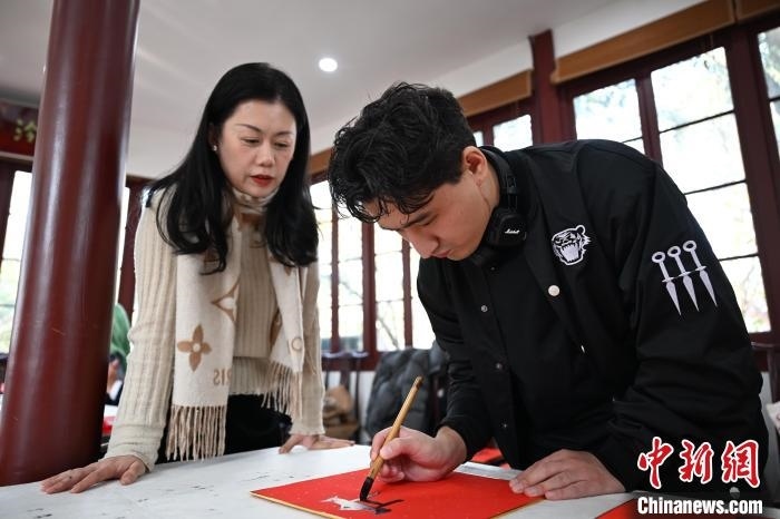 1月20日，外籍留學(xué)生在西泠印社社員李硯指導(dǎo)下寫福。當(dāng)日，來自巴西、馬來西亞、加納、哈薩克斯坦的外籍留學(xué)生在浙江杭州西泠印社體驗(yàn)福貼、春聯(lián)和篆刻，感受古老的中國傳統(tǒng)文化。中新社記者 王剛 攝