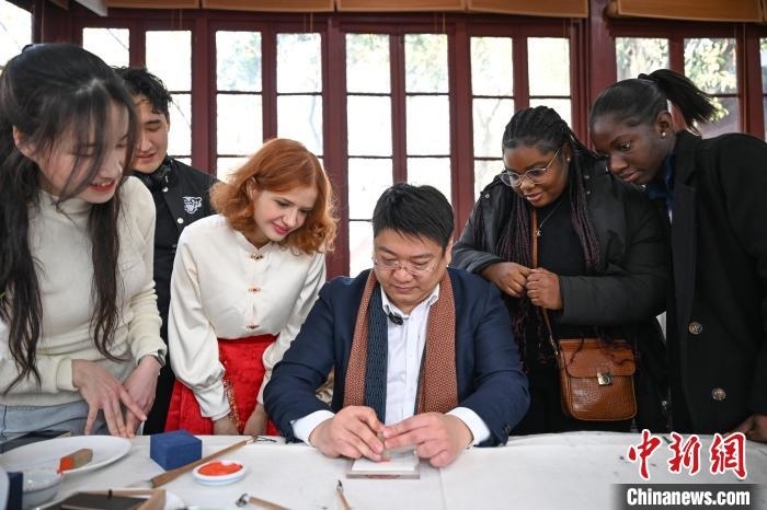 1月20日，篆刻家王臻向外籍留學(xué)生展示篆刻印章。當(dāng)日，來自巴西、馬來西亞、加納、哈薩克斯坦的外籍留學(xué)生在浙江杭州西泠印社體驗(yàn)福貼、春聯(lián)和篆刻，感受古老的中國傳統(tǒng)文化。中新社記者 王剛 攝