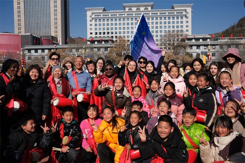 中外青年學(xué)子在安塞文化廣場觀看陜北腰鼓和大秧歌表演后合影留念，大家踏著鼓點(diǎn)共舞，翻飛的紅綢與躍動的身影交織，在黃土地廣場上繪出一幅生動的陜北民俗互動畫卷