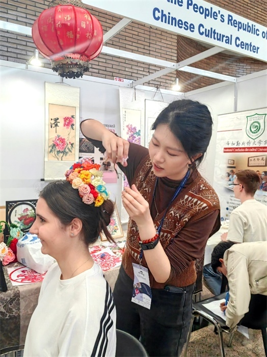 展覽正值羅馬尼亞迎春花節(jié)，國(guó)際中文教師志愿者潘婧穎向游客們介紹了國(guó)家非物質(zhì)文化遺產(chǎn)——福建泉州的簪花文化。布加勒斯特大學(xué)孔子學(xué)院供圖。