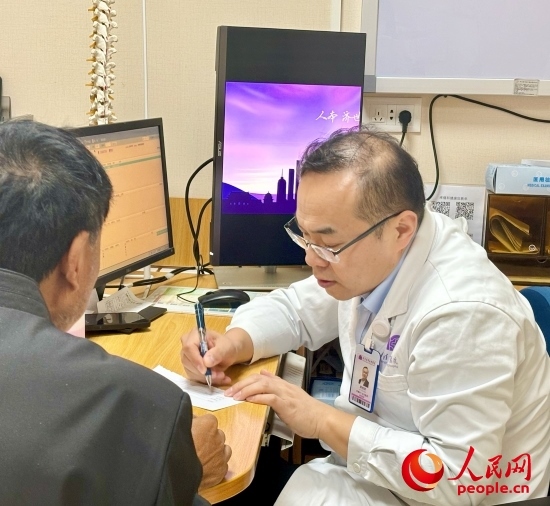 路桂軍接診時(shí)為患者寫下用藥提示。人民網(wǎng)記者 金慧慧攝