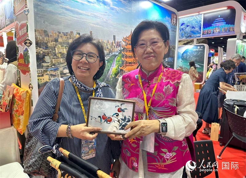 中國“大冶刺繡”傳承人劉小紅（右）參加泰國國際旅游展，向觀眾介紹中國非遺刺繡針法。人民網(wǎng)記者 簡承淵攝
