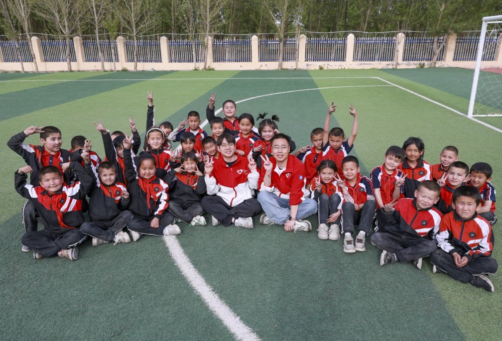 4月23日，在新疆克州阿圖什市哈拉峻鄉(xiāng)謝依特小學(xué)，支教教師王俊文（中左）、李軻凡（中右）和學(xué)生在一起。
