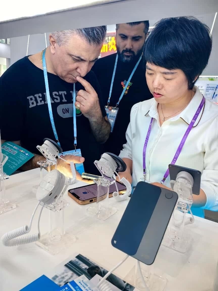 展臺工作人員向外商展示“AI TOP翻譯終端”。圖片來源：受訪者提供