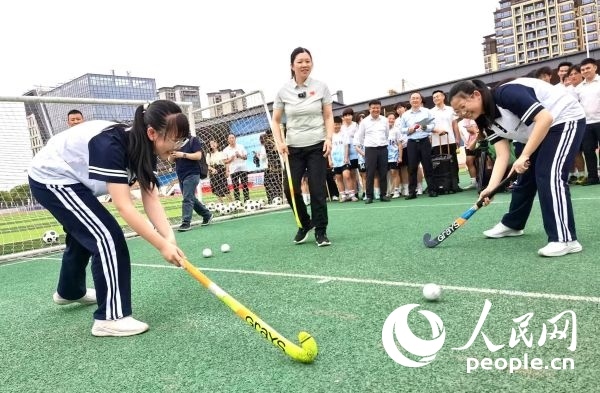 陳朝霞（中）指導學生體驗曲棍球。 人民網記者 楊磊攝