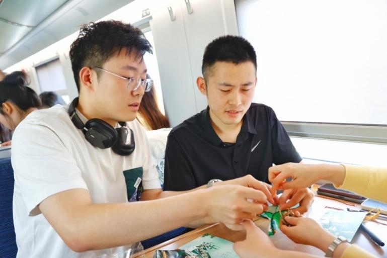 G232次旅客親手制作端午荷包和五彩繩。王磊攝